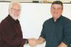 The changing of the guard. North Frontenac Public Works Manager Jim Phillips hands the reins to his replacement, Darwyn Sproule at last week’s Council meeting. Phillips did say he’d be at the Dec. 15 meeting.