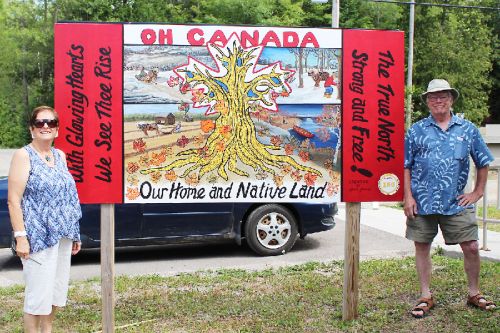 Marily Seitz and John Walters unveil the Canada 150 mural at the Ompah Community Centre. The mural, painted by local artist Gleva Lemke, features the names of many area residents. 