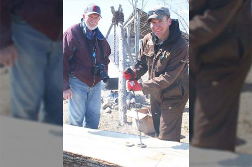 Ryan Conboy makes coasters branded with maple leaves with Ron (“the oldest one of the bunch”) Conboy while sap boils down in the background. Photo/Craig Bakay