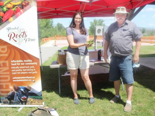 Nicole Connell of Blended Roots Farm shows Mark Revelle of Mark’s Mushrooms a handful of jalapenos at the Frontenac Farmers Market last Saturday in Harrowsmith. Photo/Craig Bakay