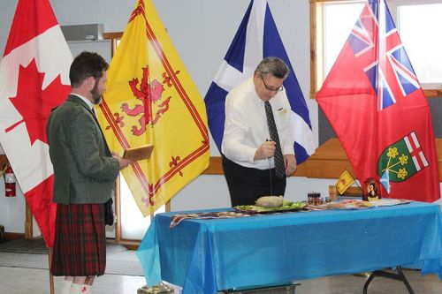 Central Frontenac Coun. Brent Cameron carves the haggis while Lanark-Frontenac-Kingston MP Scott Reid reads Robbie Burns’ Address to a Haggis in Verona Sunday. Photo/Craig Bakay