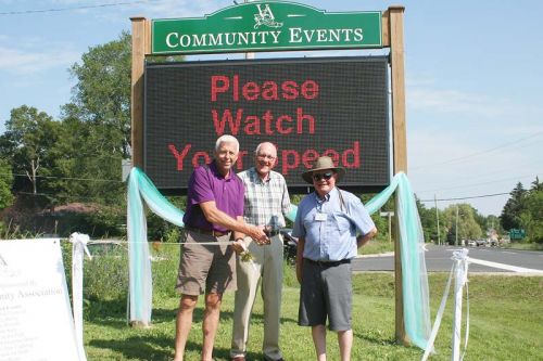 South Frontenac Mayor Ron Vandewal, Coun. John McDougall and Verona Community Association President Wayne Conway for the new electronic message board on Road 38 in Verona. Photo/Craig Bakay