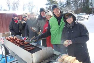  l-r, Alison Vandervelde, Marcel Giroux, Dan Bell, John McDougall, Pam Morey, Ron Vanderwal and Christine Leblanc helped hand out free sausages donated by Gilmour's on 38 at the Frontenac Community Arena for the South Frontenac Family Day and the kick off to the County's 150th Anniversary celebrations