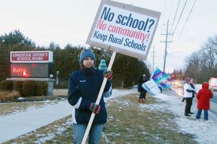 Robin Hutcheon, chair of the group called Rural Schools Matter, holds her sign outside the Limestone District School Board offices on Portsmouth Avenue in Kingston on November 8, 2017. She, along with about 30 others, are protesting the possible closure of all of the public schools in Stone Mills Township and the school in Selby.