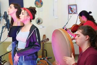 Eile and Ayisha singing, Oisin on Bodhran, and Saskia Tomkins on the fiddle