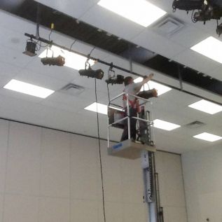 Worker removing one of 52 lights from the Granite Ridge Cafetorium on Feb. 19 - photo Joan Hollywood