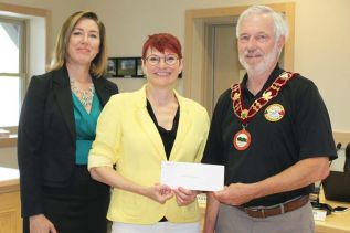 Debra Murphy (centre), Eastern Ontario regional manager for Frank Cowan Insurance and Megan Schooley from McDougall Insurance Brokers in Perth presented Mayor Ron Higgins with $5,000 from their Home Town Program to be used towards repairing Barrie Hall in Cloyne at the regular North Frontenac Council meeting last Friday in Cloyne. Photo/Craig Bakay