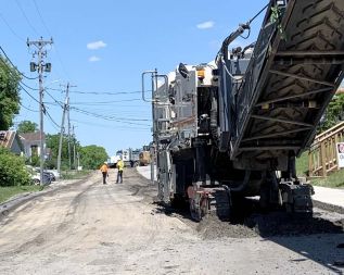 Heavy equipment roared to life in Sharbot Lake on Monday morning, (June 15) as the pavement was removed from the two side streets in the hamlet, Garrett and Robert Streets. 