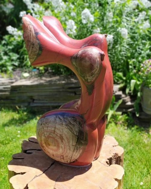 Abstract torso sculpture in Bwedzvuku red jasper semi-precious stone titled Chihera by artist Luxon Karise on cedar plinth in garden setting